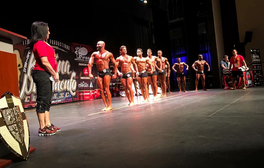 Bodybuilders lining up on stage for the judges